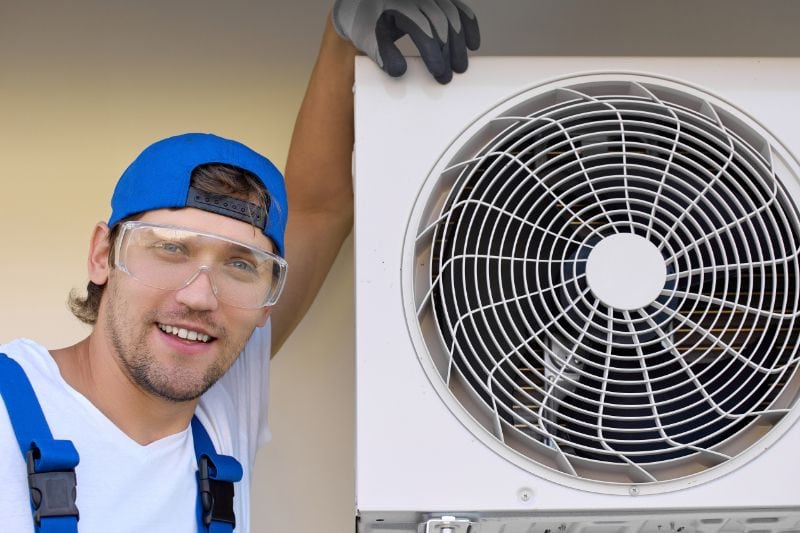 Fall HVAC Maintenance - Maintenance Worker Standing Next to HVAC System.