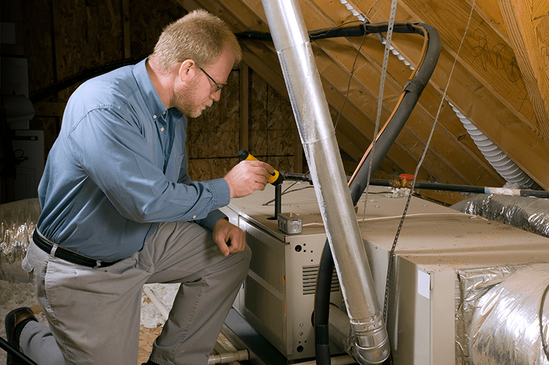 7 Furnace Maintenance Tips. Image shows HVAC professionals working on unit in attic.